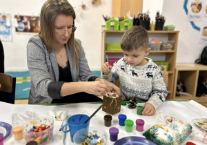 Mama z chłopcem ozdabia domek świąteczny.