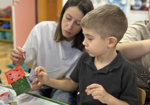 Mama z chłopcem ozdabia domek świąteczny.