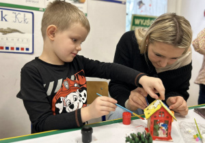 Siostra z bratem ozdabia domek świąteczny.