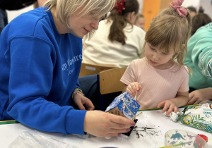 Mama z chłopcem ozdabia domek świąteczny.
