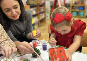 Mama z córką ozdabiają domek świąteczny.