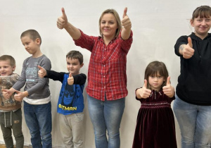 Dzieci wraz z rodzicami trzymają kciuki w górze.