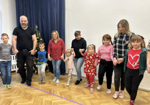 Dzieci wraz z rodzicami wchodzą do koła trzymając się za ręce.