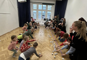 Dzieci wraz z rodzicami rzucają się kulkami z papieru.