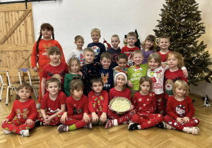 Zdjęcie grupowe - grupa IV w świątecznych piżamach. Dziecko trzyma w misce popcorn.