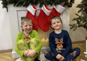 Chłopcy z grupy IV siedzą na tle dekoracji i się uśmiechają.