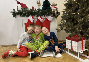 Chłopcy z grupy IV siedzą na tle dekoracji i się uśmiechają.