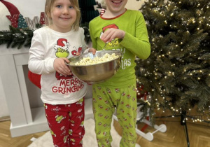 Dziewczynka z chłopcem trzymają miskę z popcornem.