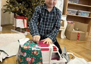 Dziecko otwiera wspólny prezent od Mikołaja.