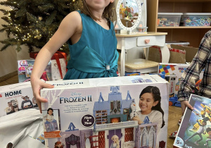 Dziecko otwiera wspólny prezent od Mikołaja.