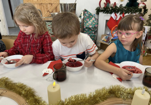 Dzieci siedzą przy stole i jedzą wigilijny obiad.
