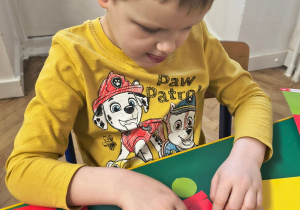 Chłopiec przykleja figury geometryczne.