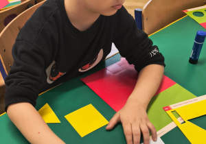 Chłopiec przykleja figury geometryczne.