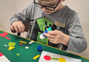 Chłopiec przykleja figury geometryczne.