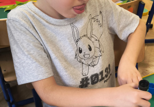 Chłopiec przykleja figury geometryczne.