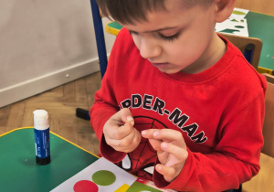 Chłopiec przykleja figury geometryczne.