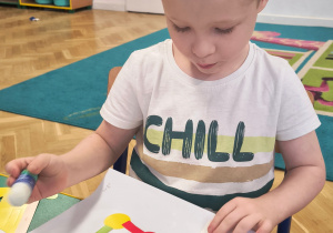 Chłopiec przykleja figury geometryczne.