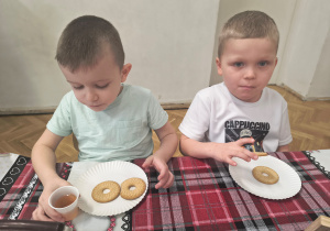 Chłopcy jedzą ciasteczka. Jeden z nich pije herbatkę.