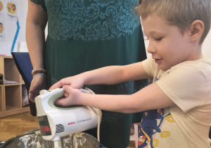 Chłopiec miesza mikserem masę budyniową.