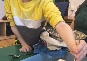 Chłopiec nakłada łyżką masę na ciasto.