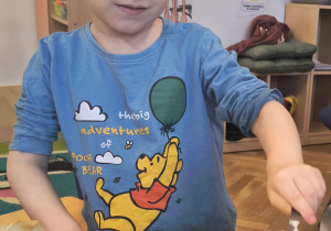 Chłopiec nakłada łyżką masę na ciasto.