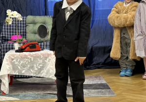 Chłopiec przebrany w garnitur i w białych okularach krzyczy.