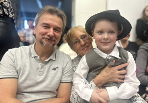 Chłopiec siedzi na kolanach u babci i uśmiechają się z dziadkiem.