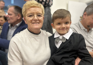 Chłopiec siedzi u babci na kolanach i uśmiechają się.