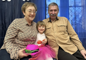 Dziewczynka siedzi pomiędzy dziadkami.