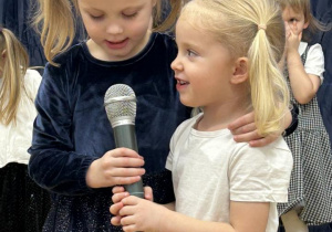 Dwie dziewczynki mówią wierszyk do mikrofonu.