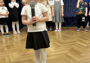 Dziewczynka mówi do mikrofonu wierszyk.