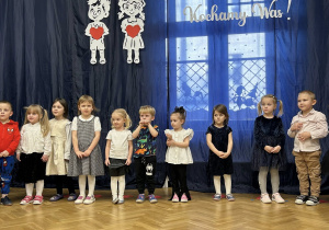 Dzieci z grupy II stoją na tle dekoracji w półkolu.