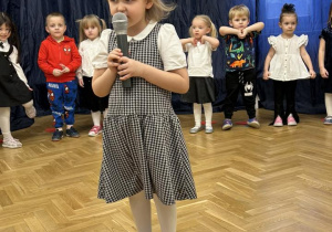 Dziewczynka mówi do mikrofonu wierszyk.