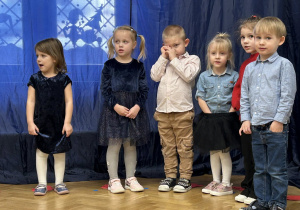 Dzieci z grupy II stoją na tle dekoracji w półkolu.