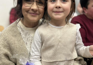 Dziewczynka siedzi u babci na kolanach, uśmiechają się.