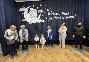 Dzieci razem z dziadkami i rodzicami trzymają się za ręce i tańczą w dużym kole.