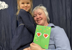 Babcia trzyma wnuczkę na rękach.