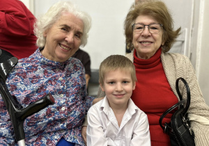 Chłopiec siedzi między Babciami, uśmiechają się.