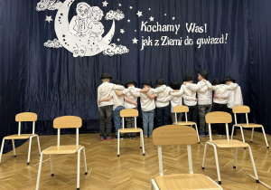 Chłopcy stoją objęci przodem do zasłony, tyłem do publiczności.