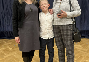 Chłopiec stoi między Babciami, uśmiechają się.