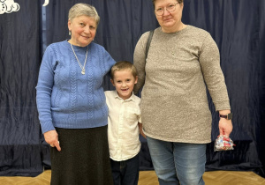 Chłopiec stoi między Babciami, uśmiechają się.