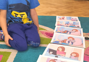 Chłopiec siedzi na dywanie przy planszach.