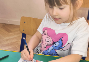 Dziewczynka koloruje kolorowankę.