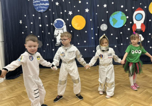 Dzieci z grupy trzeciej tańczą w kole, trzymając się za ręce.