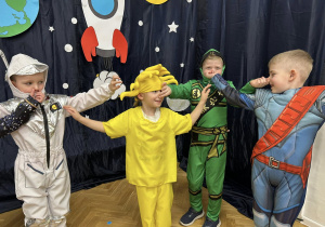 Dzieci z grupy IV tańczą w kole, trzymają się za nos.