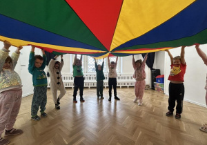 Dzieci trzymają chustę animacyjną w górze.