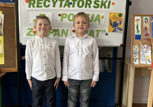 Chłopcy stoją na tle dekoracji.