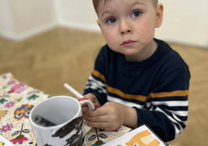 Dziecko maluje kubek.