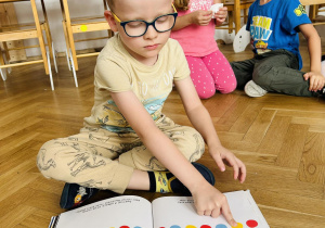 Dziecko trzyma książkę z kropkami.