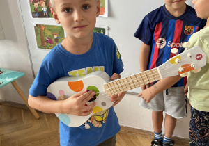 Chłopiec trzyma gitarę.